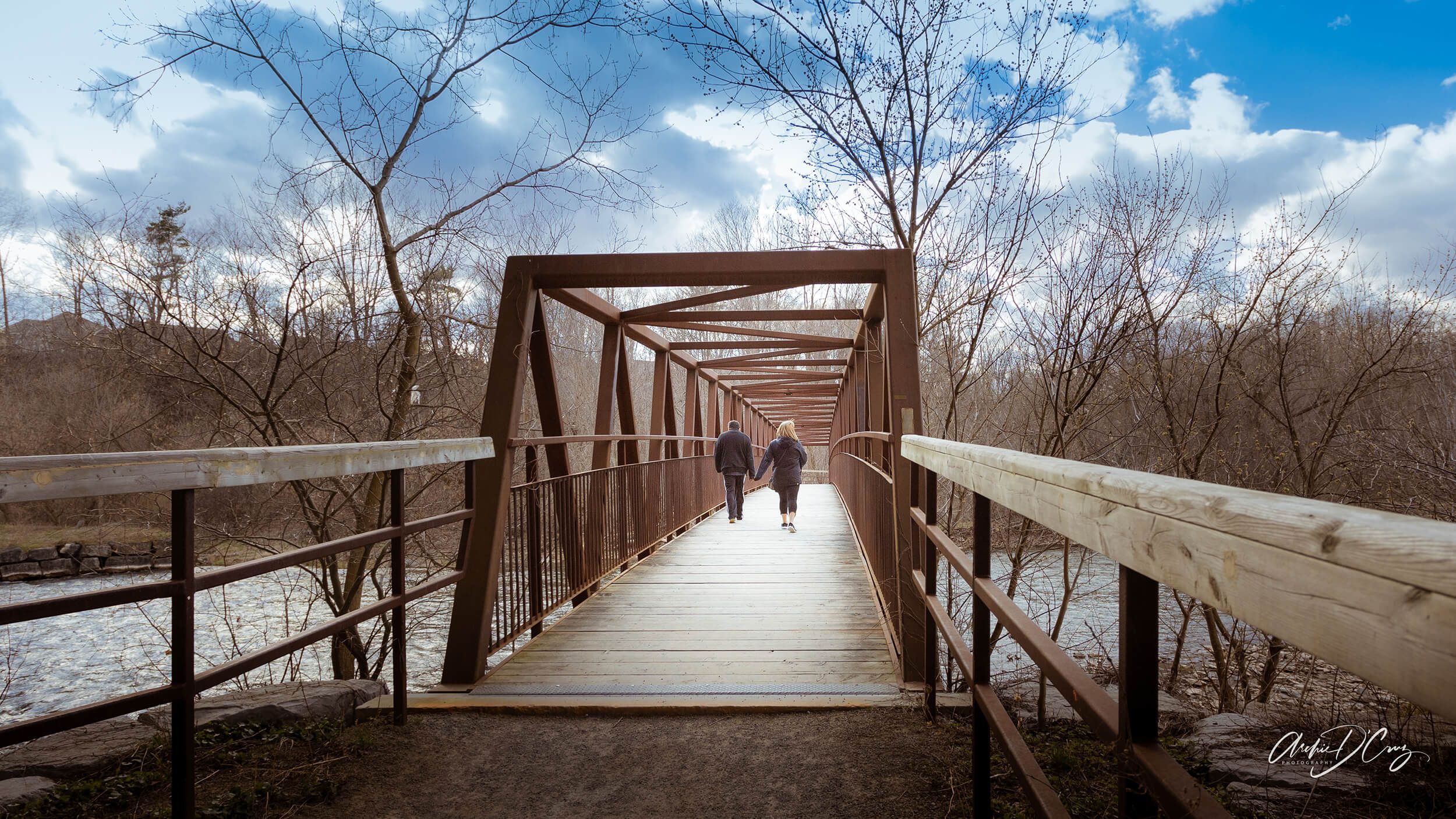 Couple walks across the trail bridge across the Credit River in Mississauga