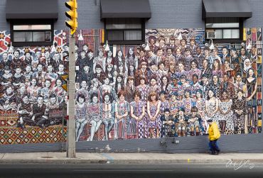A woman walks past a mural depicting a school class picture in the early 1900s
